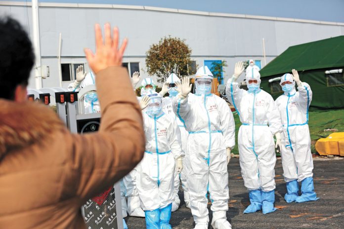Medical personnel in protective suits wave hands to a patient who is discharged from the Leishenshan Hospital after recovering from the novel coronavi