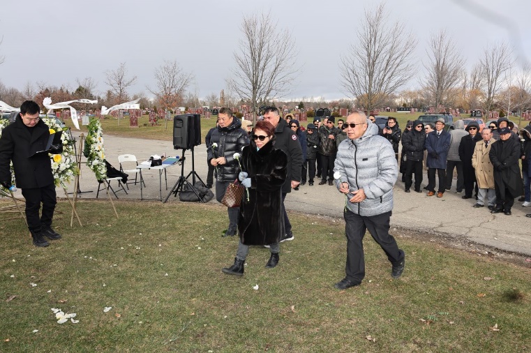 A group of people walking in a cemetery

Description automatically generated